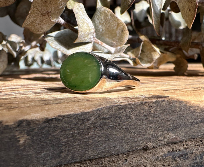 Side profile of a silver ring featuring an oval green jade cabochon and a sculpted wrap around the band.