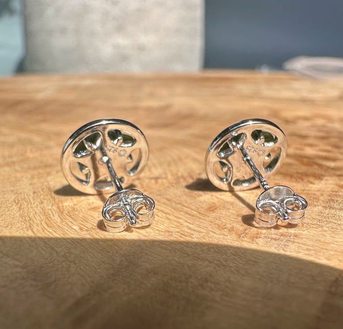 Back view of Canadian Jade Silver Star Studs showing round silver settings and butterfly backs on a wood surface