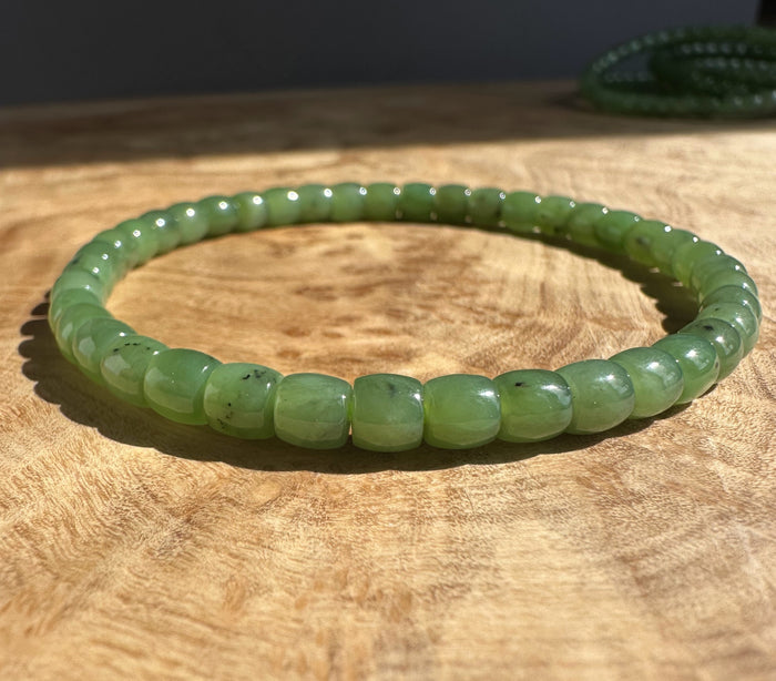 Canadian Nephrite Jade Bead Bracelet King Mountain Mine resting on a wooden surface with a dark backdrop.