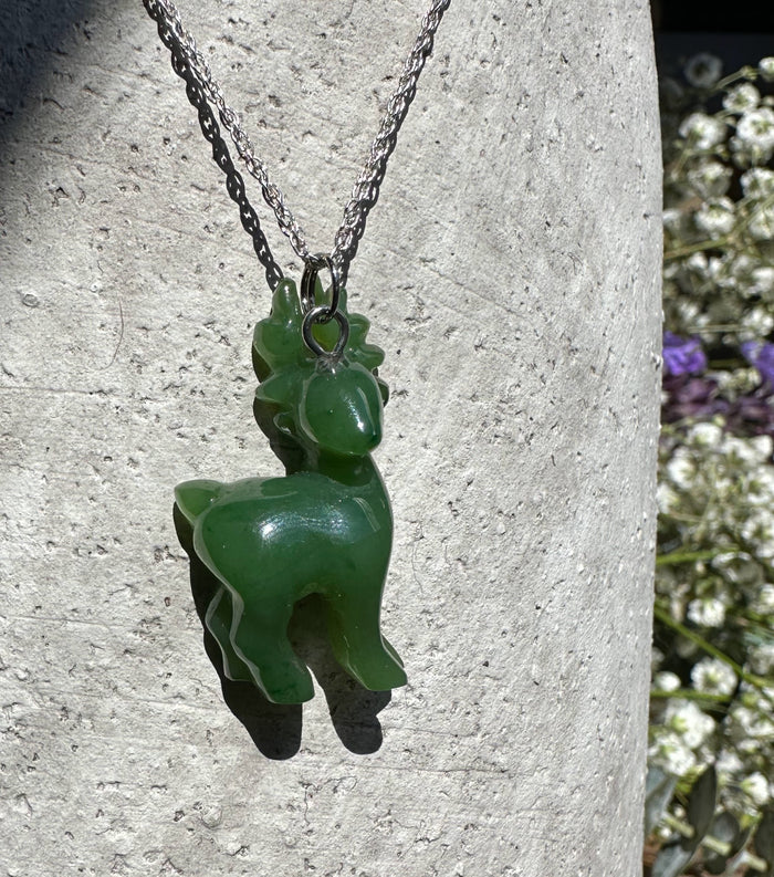 Canadian nephrite jade deer pendant on a silver chain against a textured gray stone surface