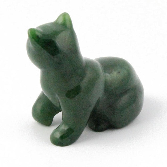 Green cat figurine lying down on a white background