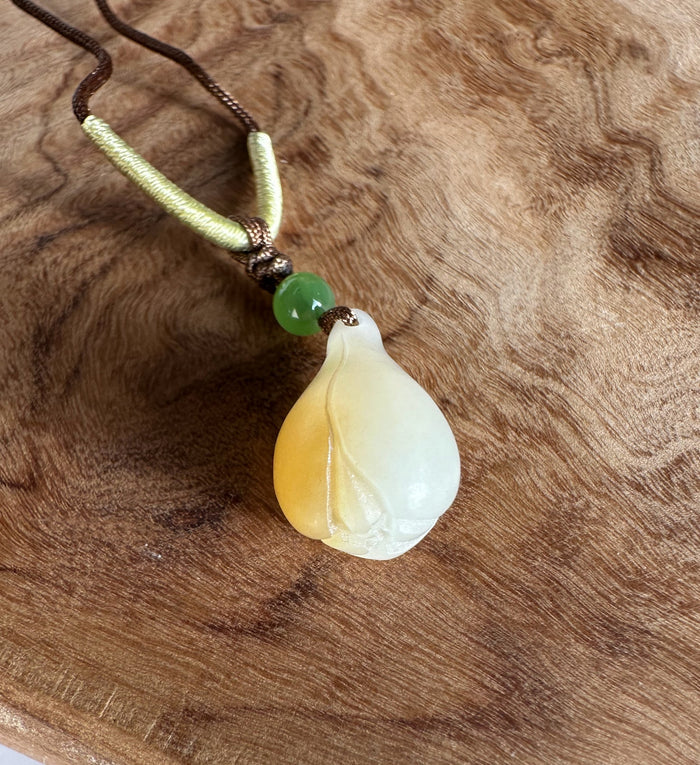 Dainty honey white nephrite jade pendant on a brown cord with a green bead