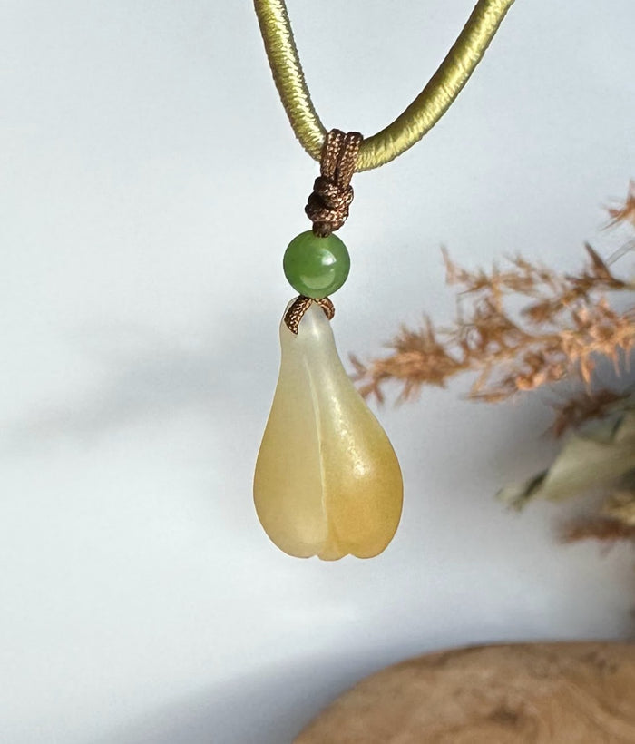 Teardrop honey white nephrite jade pendant with a green bead on an olive green cord