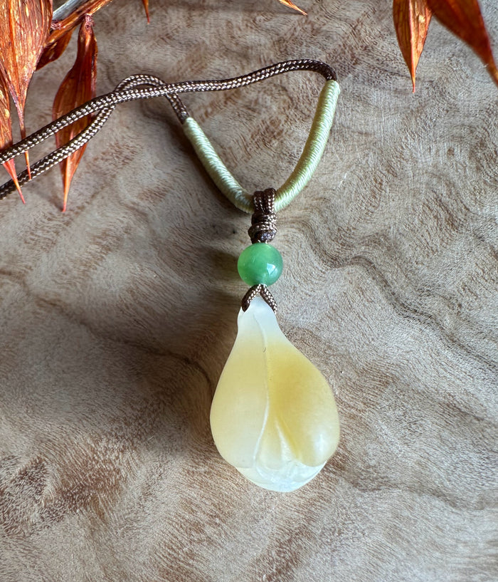 Dainty Honey White Nephrite Jade teardrop pendant with a green bead on a brown and olive cord necklace