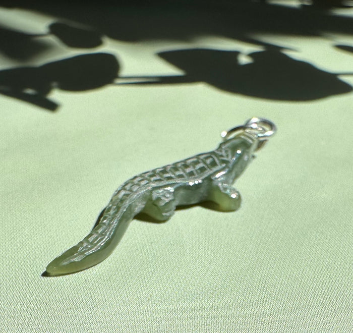 Side view of dark green jade alligator charm showing carved scales and loop