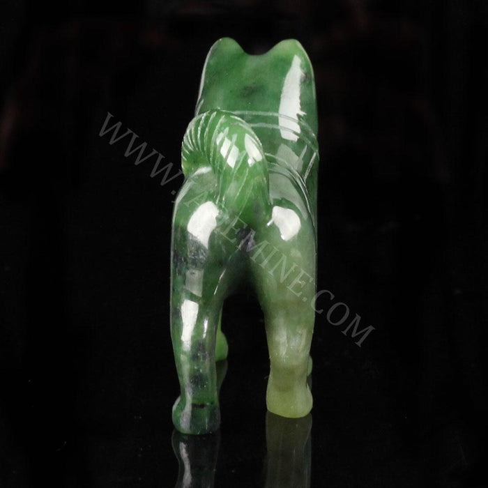 Green jade husky statue viewed from behind with curled tail on black background.