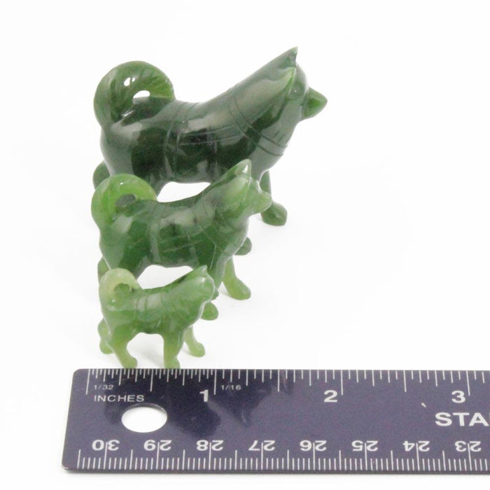 Three green jade husky figurines arranged in a row with a ruler for scale.