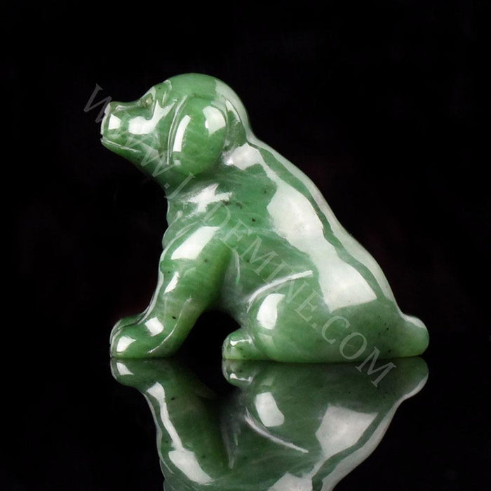 Green jade Labrador retriever figurine on a black reflective surface