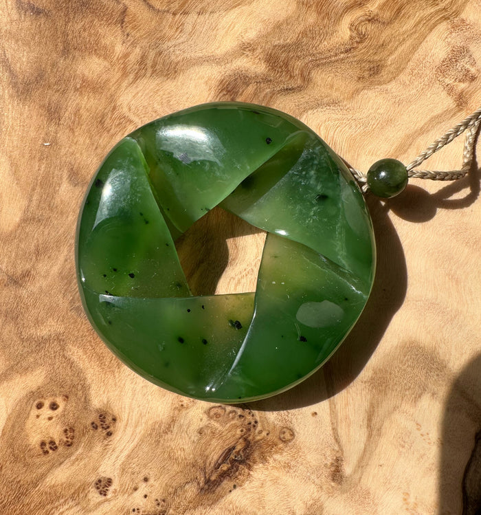 Fractured AA Nephrite Jade circular pendant with spiraling segments on a twine cord and small green bead
