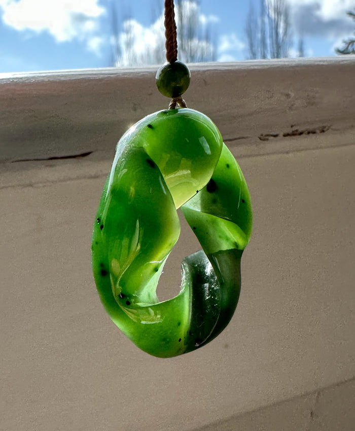 Fractured AA Nephrite Jade Spiral pendant suspended by a brown cord with a round jade bead above