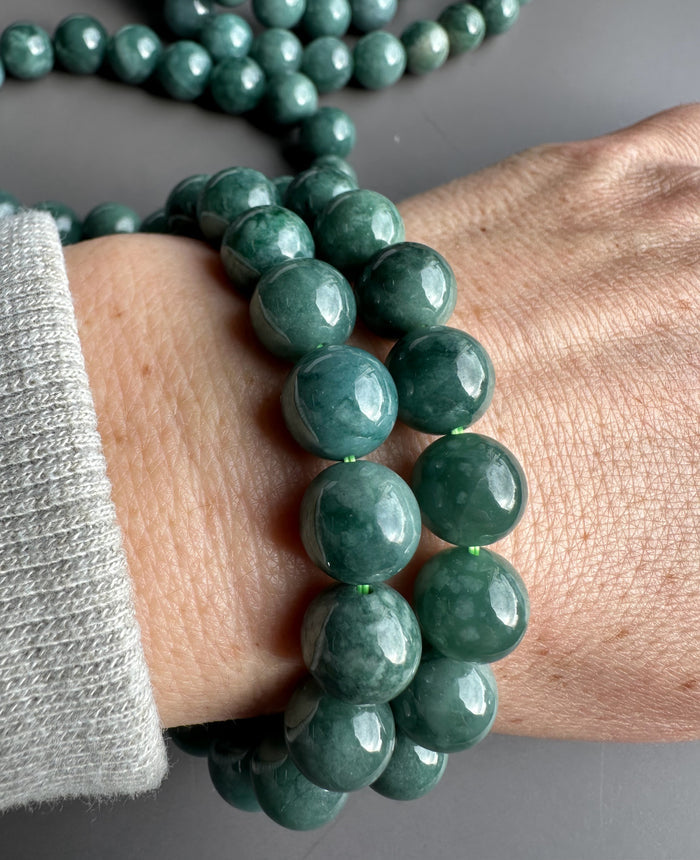 Wrist adorned with several Guatemalan jadeite bead bracelets featuring shiny green 10mm beads