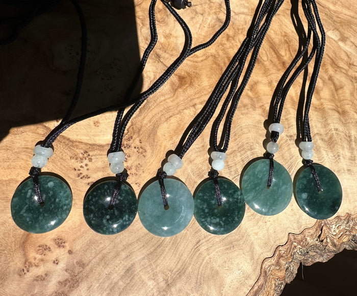Blue Green jade necklaces on black cords with small beads on a wooden surface