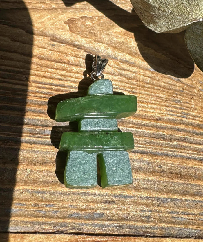Inukshuk pendant 25mm with stacked green stones and a silver bail resting on a wooden surface.