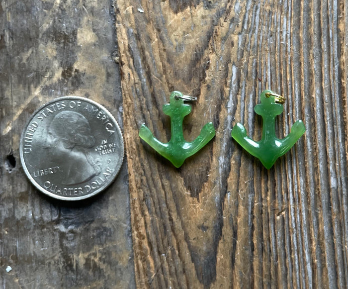 Two green jade anchor charms shown beside a quarter for scale