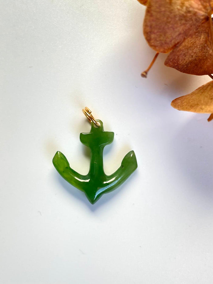 Single green jade anchor charm with a gold bail on a light background