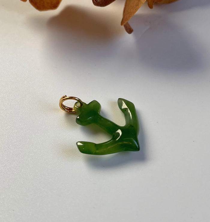 Green jade anchor charm with a gold loop attachment.