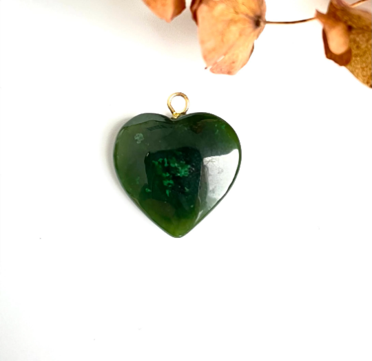 Polished jade heart pendant with a small gold bail on a white background