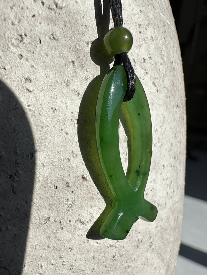Green jade Ichthys pendant on a black cord with a small round bead above, 30mm.
