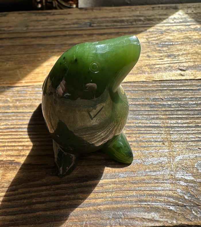 Close up of green jade seal showing glossy head and carved base on wood