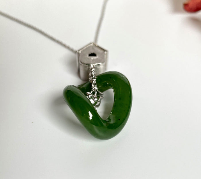 Jade green circular pendant on a silver chain with a birdhouse charm.