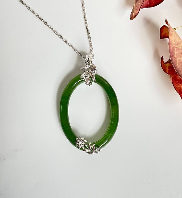 Jade green 35mm oval pendant in a silver setting with a leaf cluster at the top and floral detailing at the bottom.