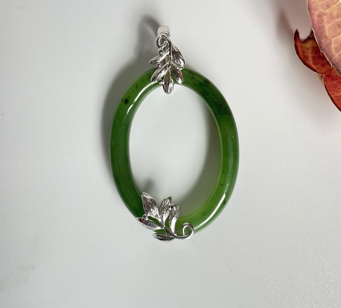 Bright green jade oval pendant with silver leaf accents at the top and bottom
