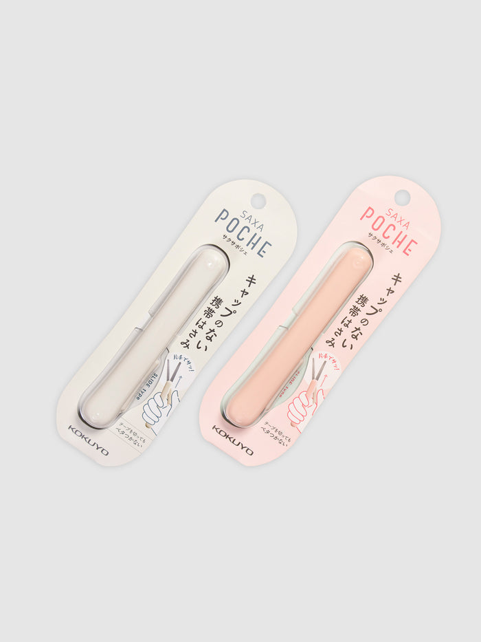 Kokuyo Saxa Poche Compact Scissors in White and Peach arranged parallel to each other against a neutral background. Both scissors are turned slightly to the right.