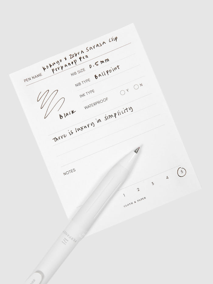Kokuyo x Zebra Sarasa Clip Perpanep Pen, Cloth and Paper. Pen resting on pen test sheet displaying writing sample.