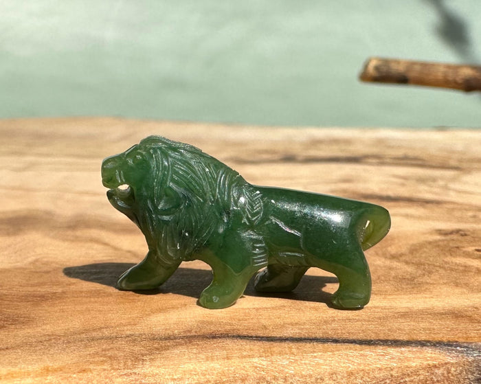 Green jade carved lion figurine standing on a wooden surface