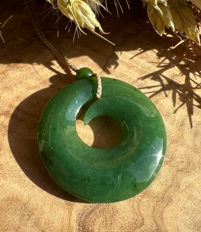 Donut shaped green pendant with a central hole hanging from a cord.