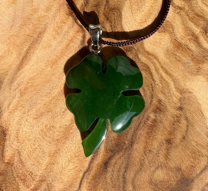 Green shamrock pendant on a brown braided cord against a wooden surface