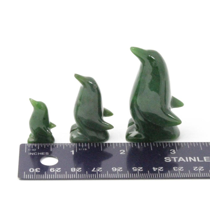 Three green penguin figurines of different sizes with a ruler for scale.