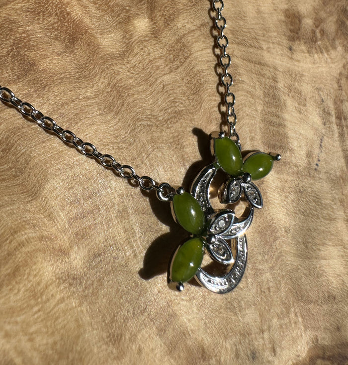 Silver butterfly pendant with lime green leaf shaped stones and ornate metalwork on a chain.