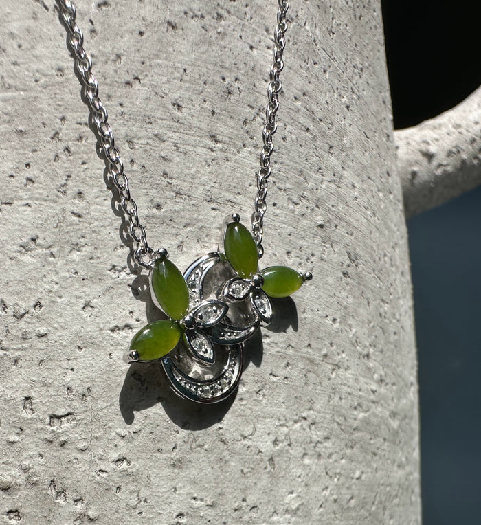 Close up of silver butterfly pendant with lime green leaf stones and clear crystal accents on a silver chain.
