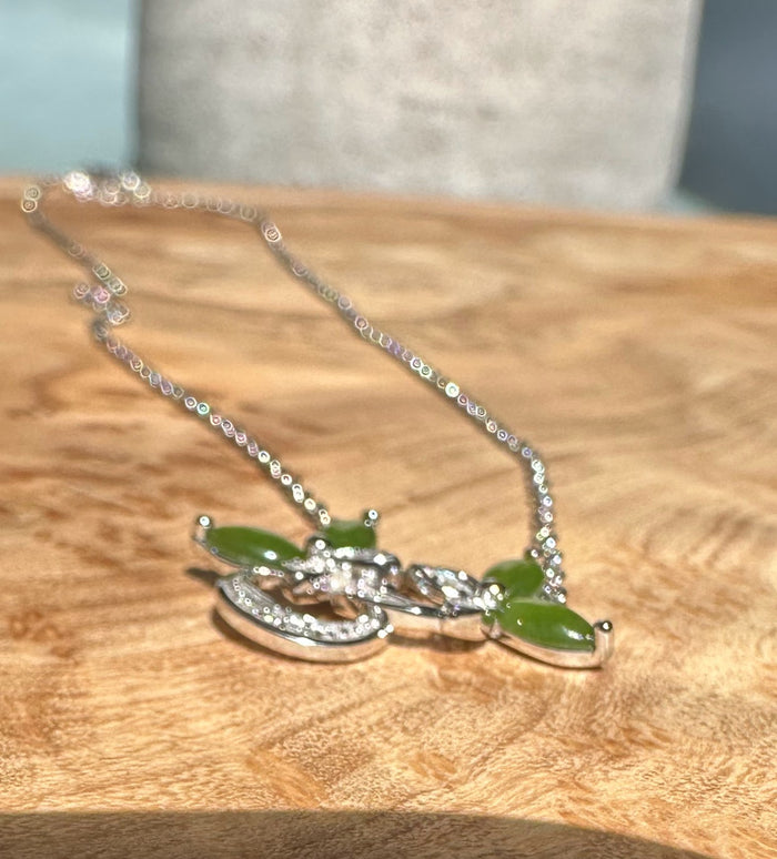 Silver butterfly pendant with green stones and crystal accents on a delicate chain