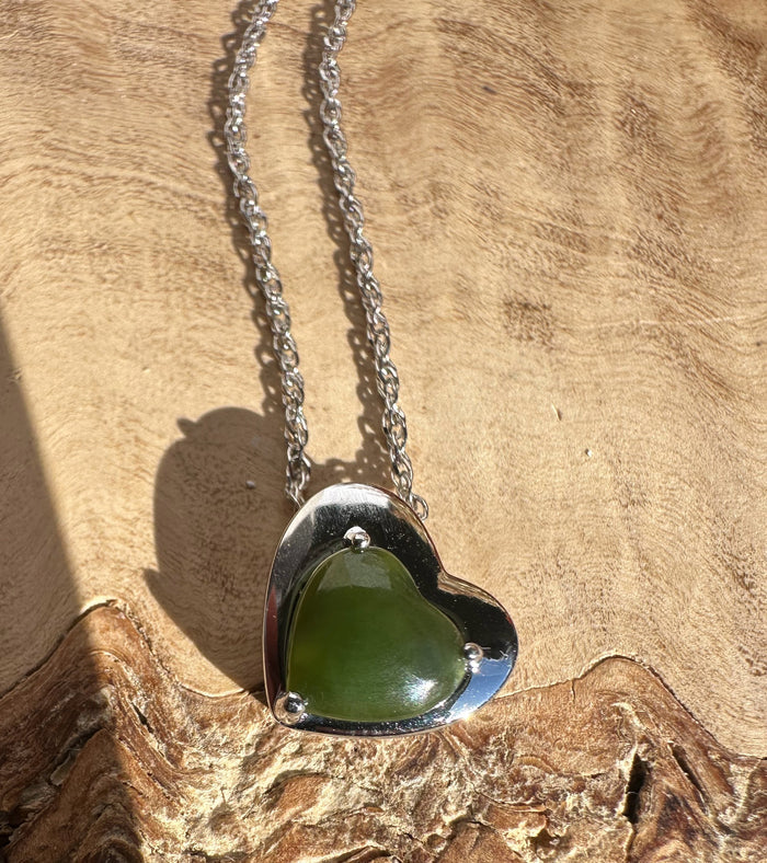Silver heart pendant encasing a green heart shaped stone on a chain