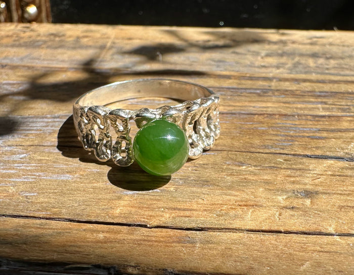 Silver ring with a round green jade cabochon in a textured openwork band.