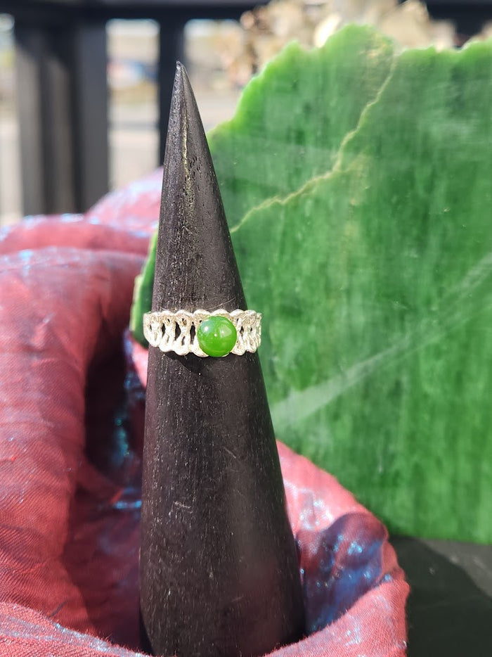 Close up of Silver Jade Ring featuring a round green jade stone on a detailed silver band atop a black display cone