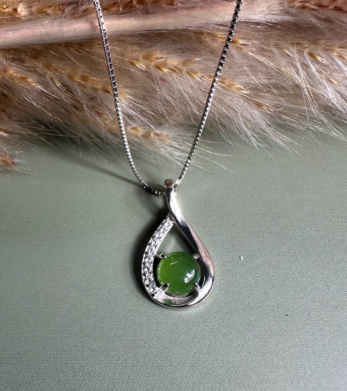 Silver Infinity pendant featuring a green center stone held inside a teardrop shaped frame with diamonds along the inner curve