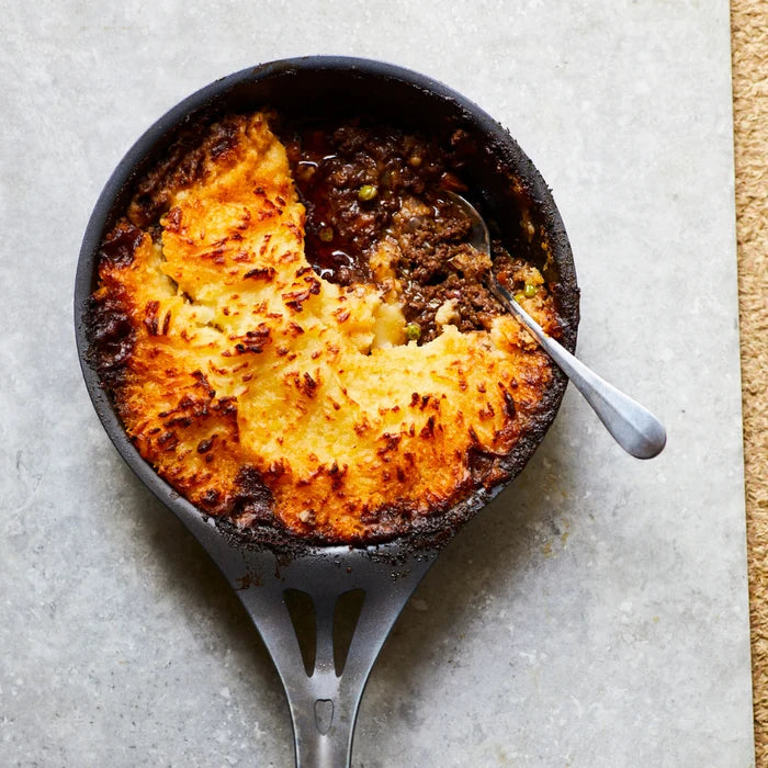 Half eaten shepherd's pie in a black carbon steel fry pan that has super crispy mashed potatoes on top