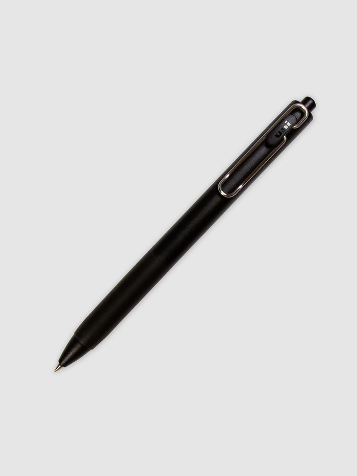 Uni One Gel Pen, 0.38 mm, Black Ink, Black Barrel, Cloth and Paper. Pen with nib exposed turned to the right against a neutral background.