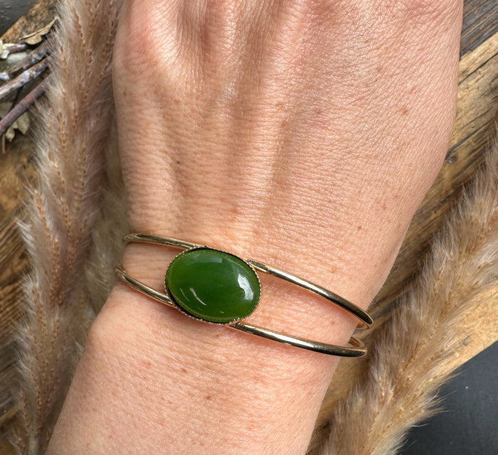 Wrist shot of Vintage Jade Bracelet featuring a green oval jade on a gold-tone double-band cuff
