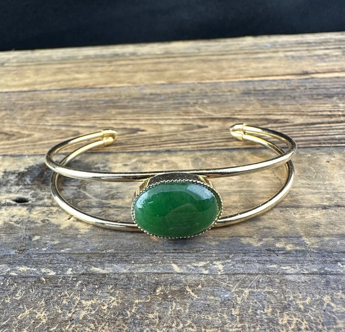 Vintage Jade Bracelet with green oval jade set in a gold-tone bezel on a rustic wooden surface