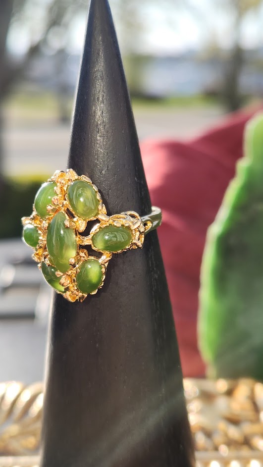 Vintage Jade Ring featuring a cluster of green jade cabochons set in gold on a black display cone.