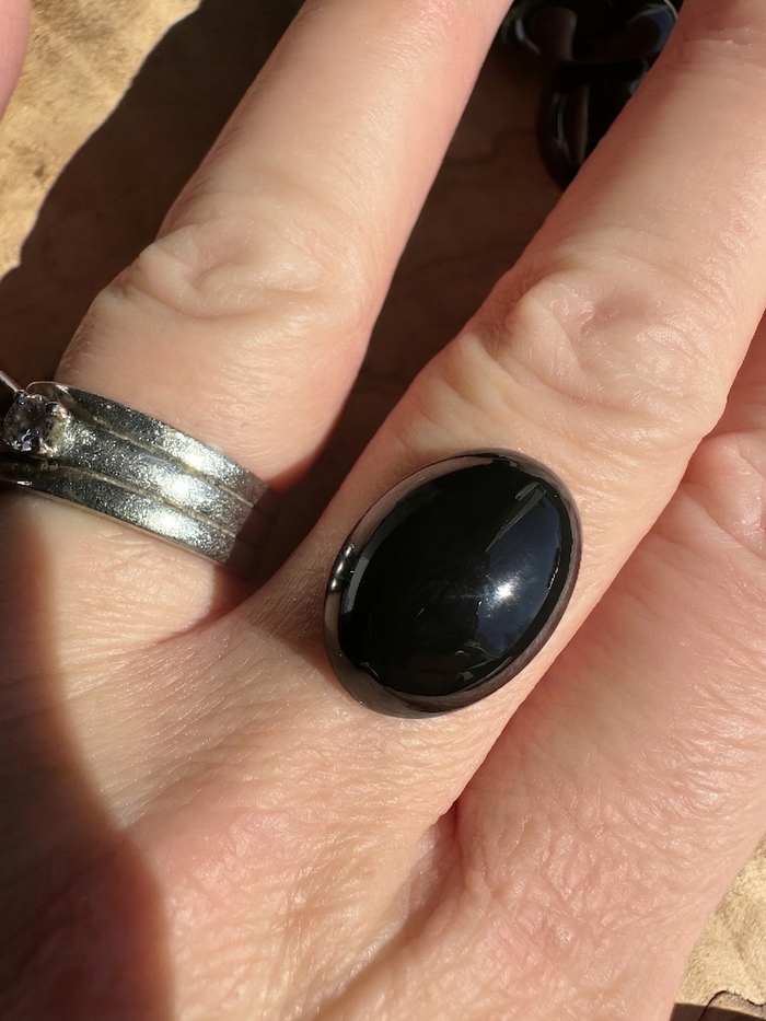 Large polished oval black Jade cabochon set in a silver ring worn on a finger