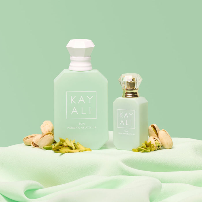Two perfume bottles labeled 'KAYALI' on a light green fabric background with flowers.